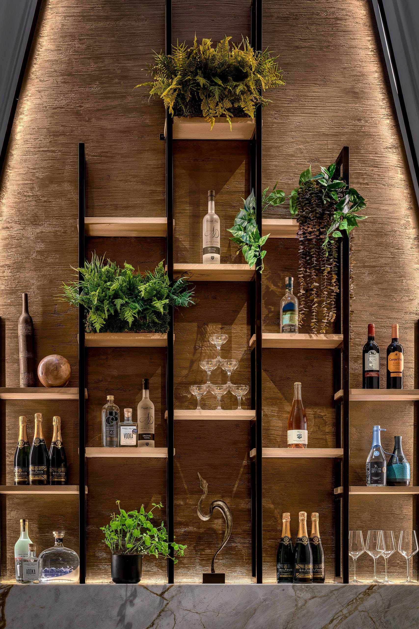 Bronze metal bar with cocktails and alcohol bottles on shelving